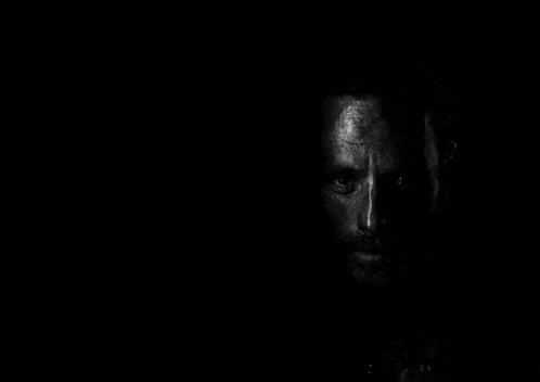 it is a black and white photo of a man 's face in the dark .