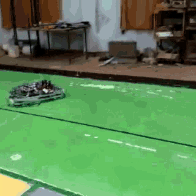 a green floor in a room with a table and a laptop