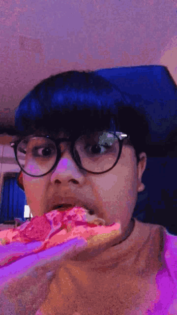 a person wearing glasses is eating a piece of pizza
