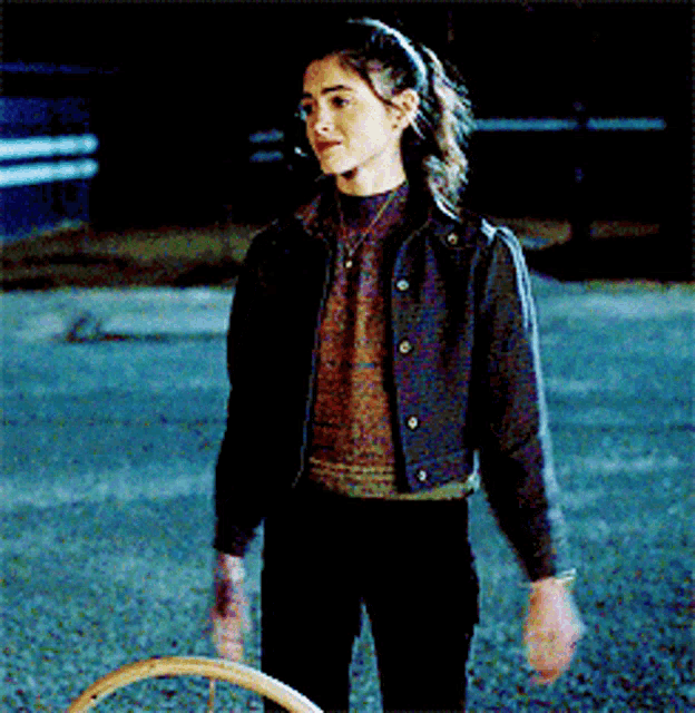 a girl in a denim jacket is holding a hula hoop