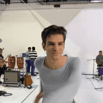 a man in a blue shirt is smiling in front of a group of musicians