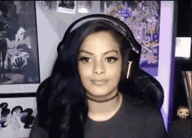 a girl wearing headphones and a choker is sitting in a chair .