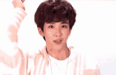 a young man wearing a pink sweater and a white shirt is making a funny face .