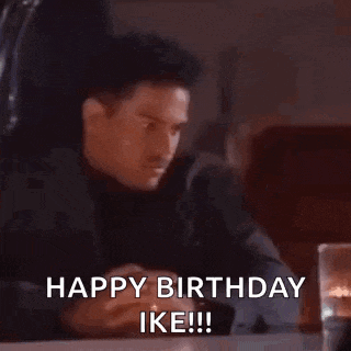 a man is sitting at a table with his hands on a keyboard and says `` happy birthday ike '' .