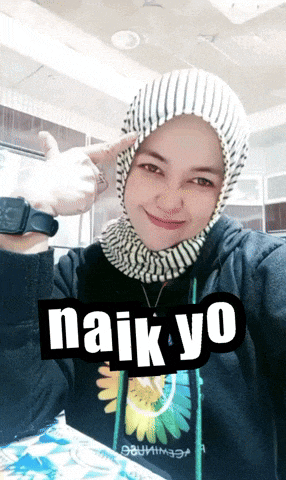 a woman wearing a hijab is giving a thumbs up and has the word naik yo on her sweatshirt