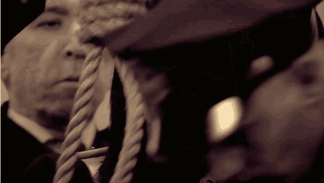 a man with a rope around his neck and another man behind him