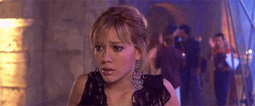 a woman wearing a black dress and earrings is looking at the camera