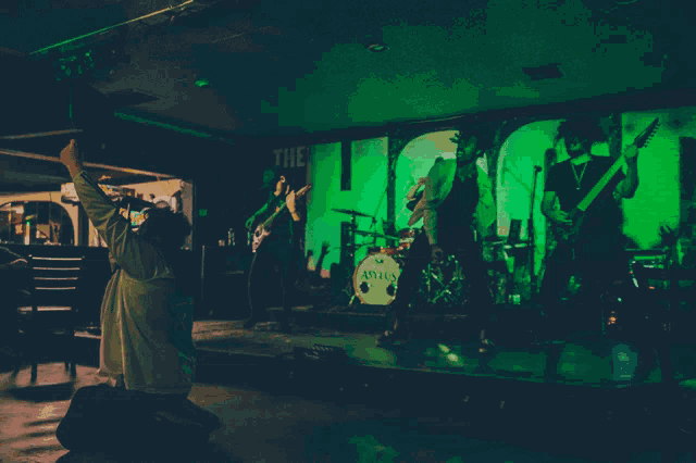 a band is playing in front of a green sign that says the loo