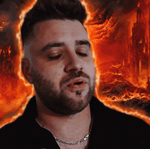 a man with a beard wearing a chain around his neck stands in front of a fire background