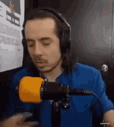 a man wearing headphones is standing in front of a microphone .