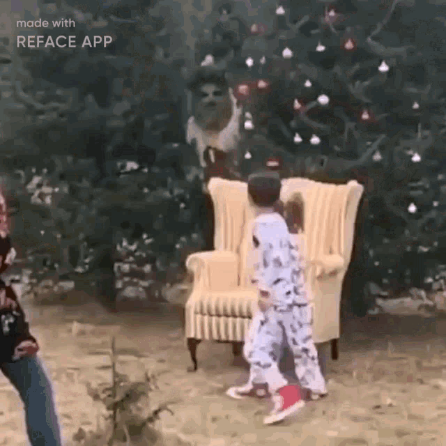 two children are standing in front of a christmas tree and chair .