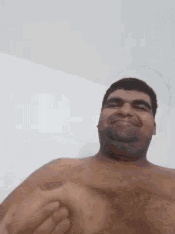 a shirtless man is smiling while holding his chest .