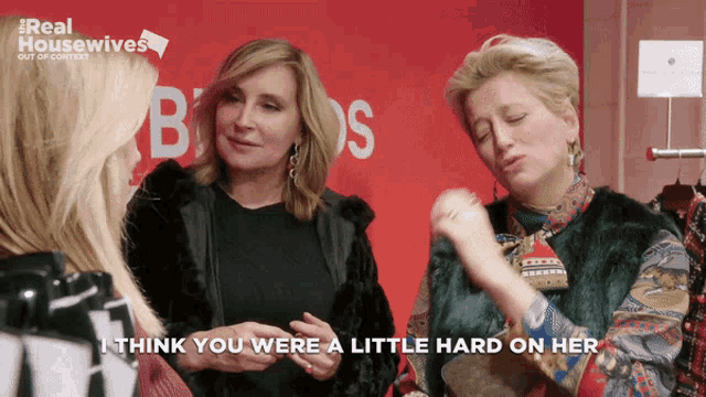 two women are talking in front of a sign that says real housewives out of context