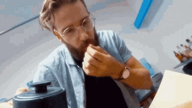 a man with glasses and a beard is eating a piece of food