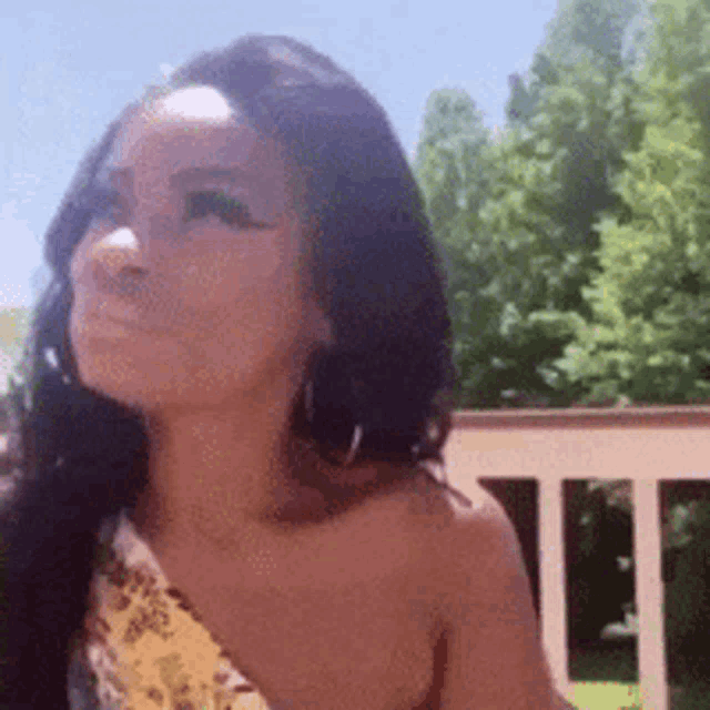 a woman wearing hoop earrings and a yellow top is standing on a balcony .