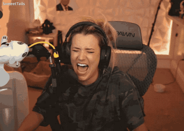 a woman wearing headphones is screaming in front of a pawn gaming chair