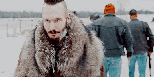 a man wearing a fur coat is standing in the snow