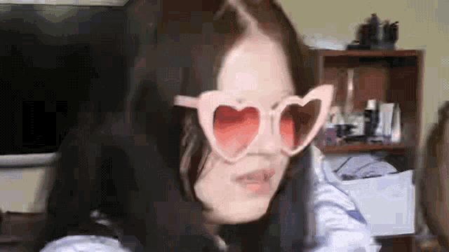 a woman wearing heart shaped sunglasses is making a funny face