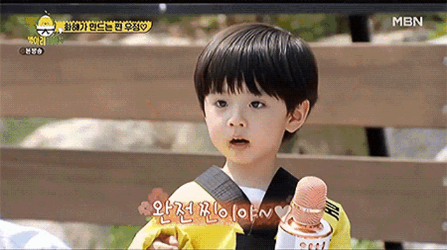 a little boy is sitting on a bench holding a microphone and a flower .