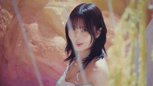 a close up of a woman wearing a white dress and pearls looking at the camera .