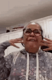 a woman wearing glasses is covering her ears with her hands .