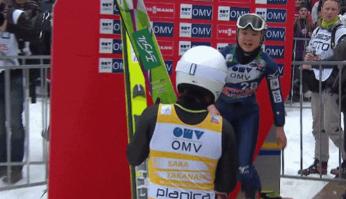 a person wearing a yellow omv vest stands next to another person