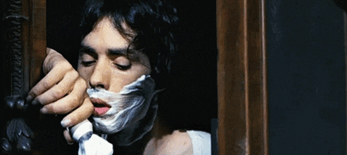 a man shaving his face with a tube of shaving foam