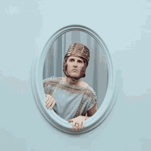 a man in a helmet is waving his hand in a picture frame with the letter m above him