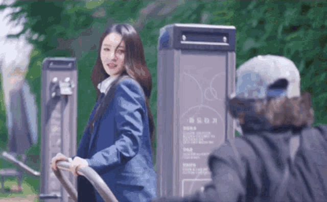 a woman in a suit is riding a bike in front of a sign that says ' park ' on it
