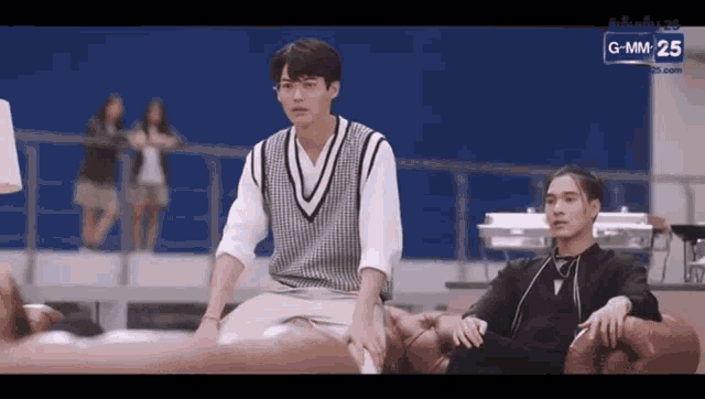 a couple of men are sitting on a couch .