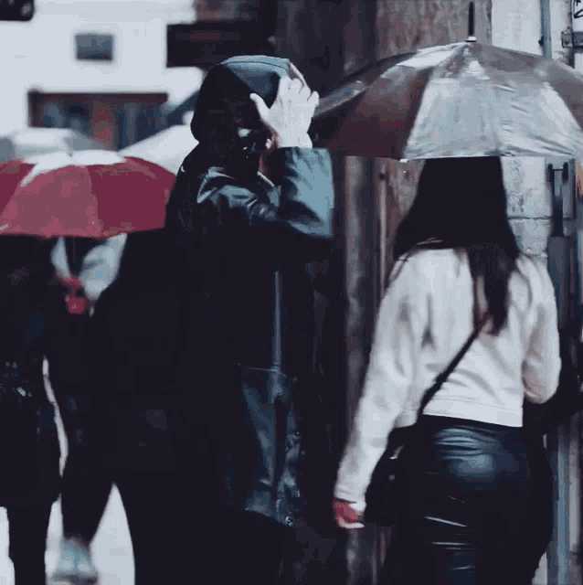 a man in a black jacket holds an umbrella over a woman 's head