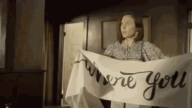 a woman is holding a large piece of paper that says `` where you '' .