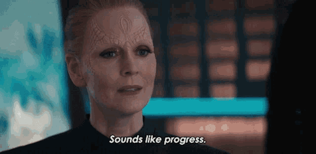 a woman with a tattoo on her forehead says " sounds like progress "