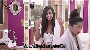 two women are standing next to each other in a room with purple walls and a sign that says secret story .