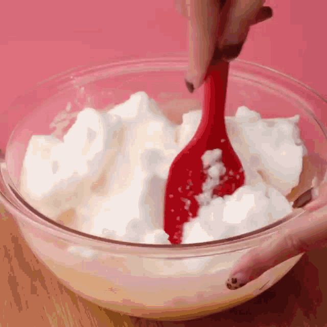 a person is mixing whipped cream with a red spoon
