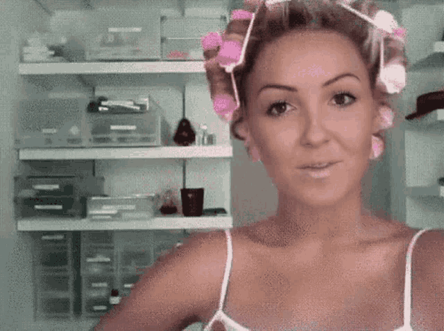 a woman with pink curlers in her hair is taking a selfie