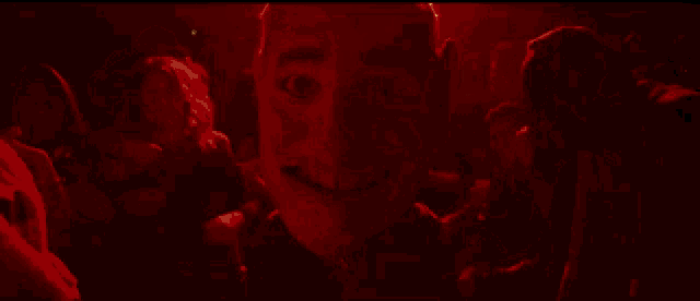 a group of people are dancing in a dark room with a mask in the foreground