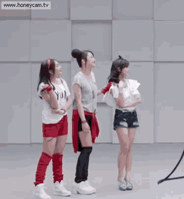 three girls are standing in front of a wall with the word irit written on it