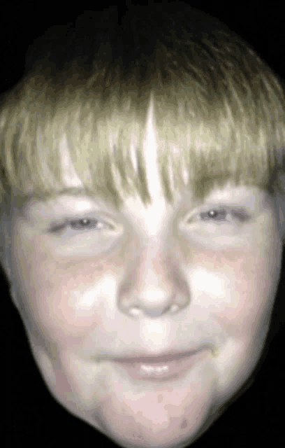 a close up of a child 's face with a slight smile on his face