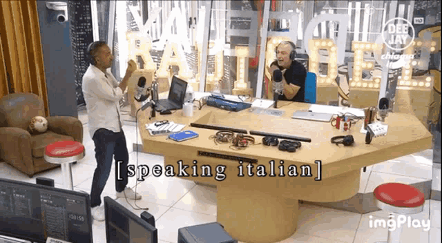 a man is standing in front of a table with the words speaking italian written on it