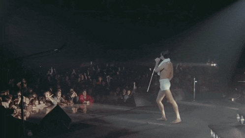 a man without a shirt is dancing in front of a microphone