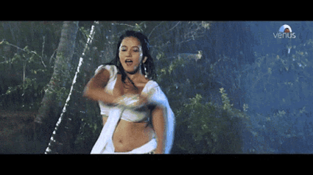 a woman in a white saree is dancing in the rain with venus written on the bottom of the screen