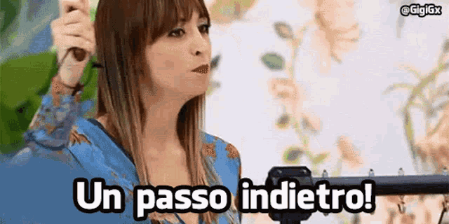 a woman in a blue dress is holding a microphone and says un passo indietro !