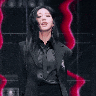 a woman in a black jacket is making a heart with her hands