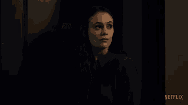 a woman in a dark room with a netflix logo on the bottom right