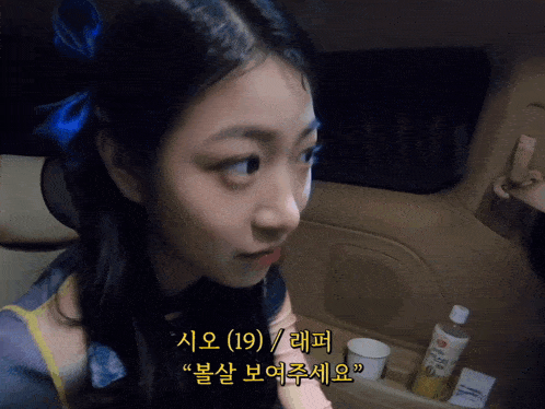 a girl with a blue bow in her hair is sitting in the back seat of a vehicle