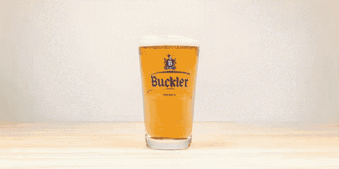 a glass of buckler beer is on a wooden table