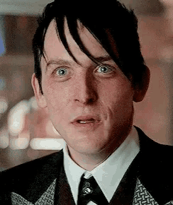 a close up of a man wearing a suit and tie making a funny face .