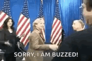 a woman is shaking hands with a man in front of american flags and says `` sorry , i am buzzed ! ''