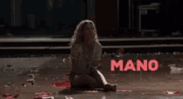 a woman is sitting on the floor in front of a sign that says ' manoe ' on it .
